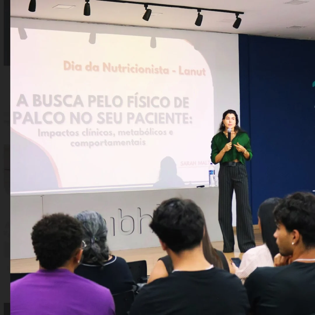 Sarah em palestra, com apresentação sobre a busca pelo físico de palco